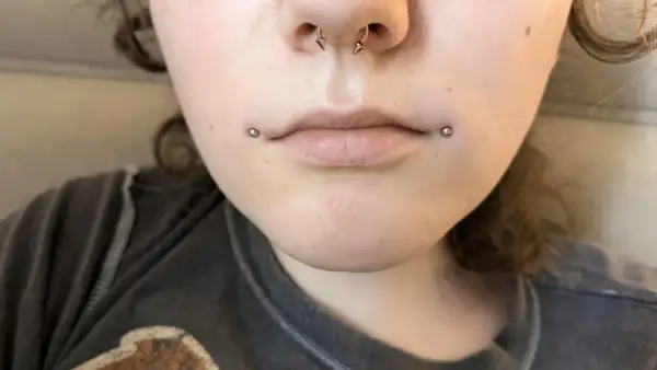 Dwa kolczyki dahlia piercing zdobią usta, dodając odważnego charakteru.