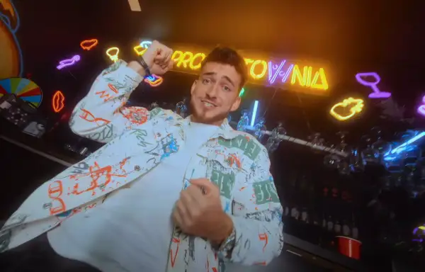 Hej, co zrobiłaś? Jaka głupia byłaś! Młody mężczyzna w kolorowej kurtce tańczy na tle neonów i baru.