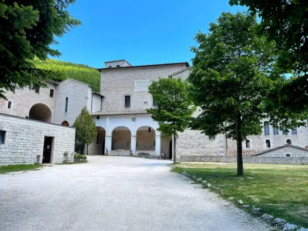 Cortile di un antico complesso monastico in pietra, con un portico ad archi. Ideale per chi cerca la fonte avellana come arrivare.