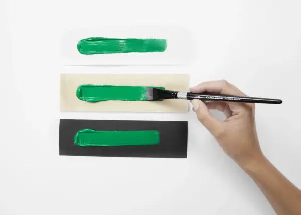 Pennello stende vernice acrilica su carta bianca, legno e nera. La vernice acrilica a cosa serve? A creare effetti vibranti su diverse superfici.
