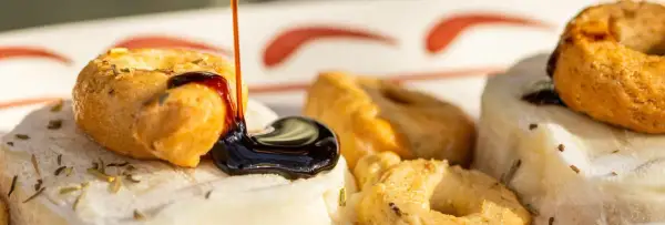 Une délicieuse entrée italienne : des taralli croustillants arrosés de glaçage balsamique sur un lit de fromage frais aux herbes.