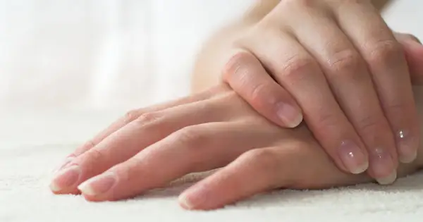 Delikatne dłonie z naturalnym, błyszczącym manicurem biologicznym. Paznokcie zadbane, z subtelnym połyskiem.