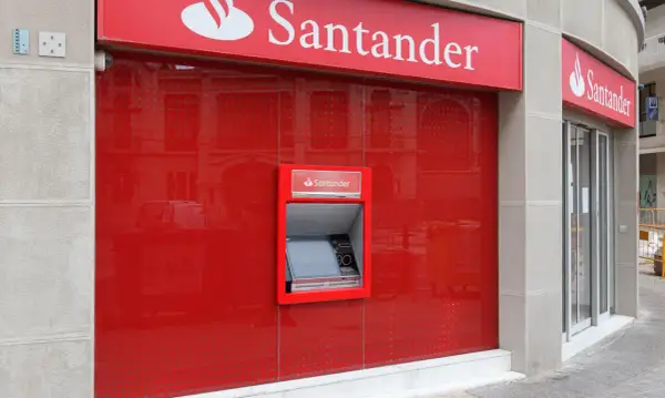 Bankomat Santander Platinum Konserwatywny na czerwonej, lśniącej ścianie.