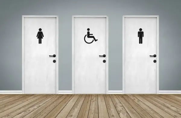 Trois portes blanches avec des pictogrammes : femme, homme et une porte pmr au centre.