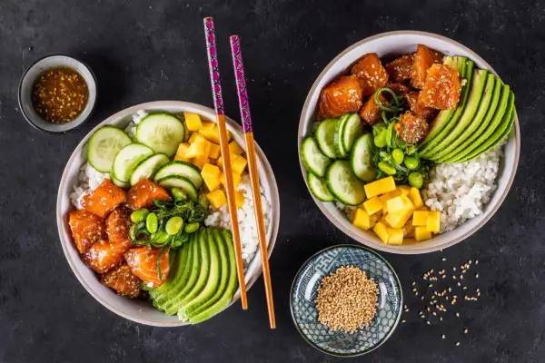 Zwei bunte Sushi Bowls mit Lachs, Avocado, Gurke, Mango und Edamame. Perfekte sushi bowl zutaten für einen gesunden Genuss.