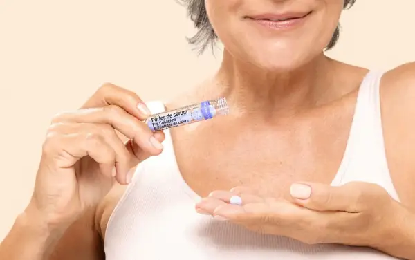 Une femme tient une perle de sérum contenant des peptides, prête à l'appliquer pour un soin anti-âge.