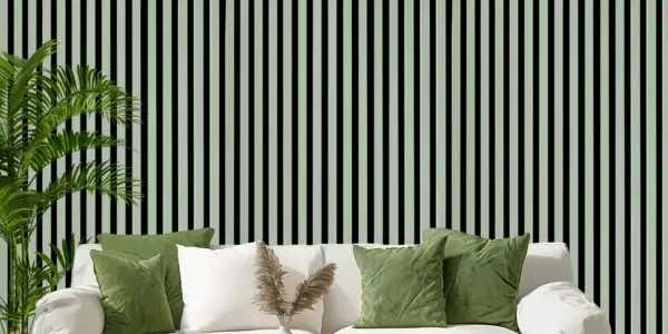 Grüne Kissen auf weißem Sofa vor vertikal gestreifter Wand. Akustikpaneele verbessern den Raumklang und die Ästhetik.