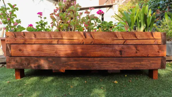 Mesa de cultivo de madera con flores y plantas verdes. Ideal para aprender cómo hacer una mesa de cultivo.