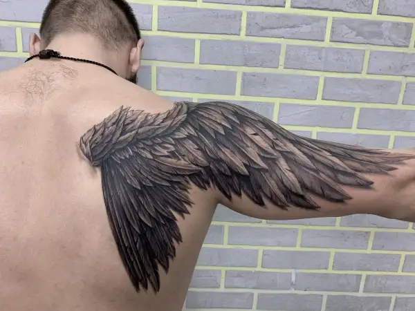 Realistyczny tatuaż skrzydła na ramieniu. Symbolika wolności i siły.