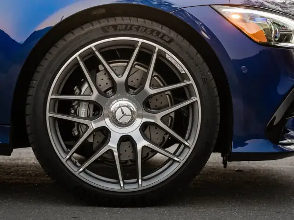 Primo piano della ruota di un'auto blu con cerchi AMG e dischi freno forati, per un controllo freni auto impeccabile.