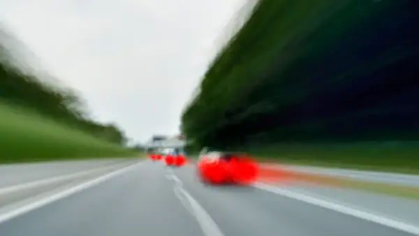 Dynamiczne wyprzedzanie z lewej strony na autostradzie. Czerwone światła samochodów zamazane przez ruch.