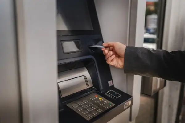 Dłoń wsuwa kartę do bankomatu PKO. Zastanawiasz się, ile można wyplacic w bankomacie PKO? Sprawdź to!