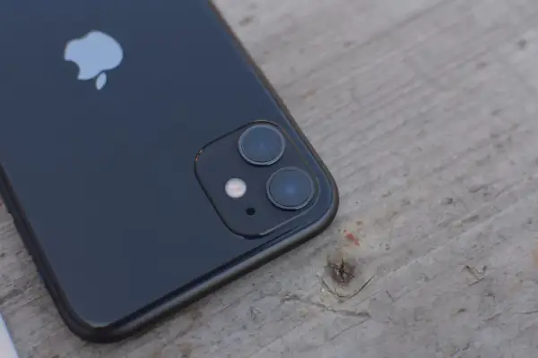 Czarne iPhone'a z podwójnym aparatem na drewnianym tle. Dowiedz się, jak wyłączyć Live Photo.