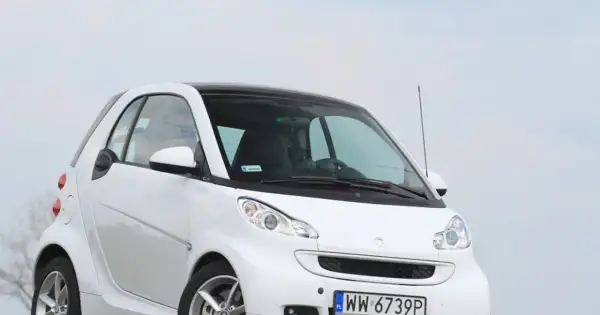 Biały smart fortwo 451 z czarnym dachem, zaparkowany na tle nieba.