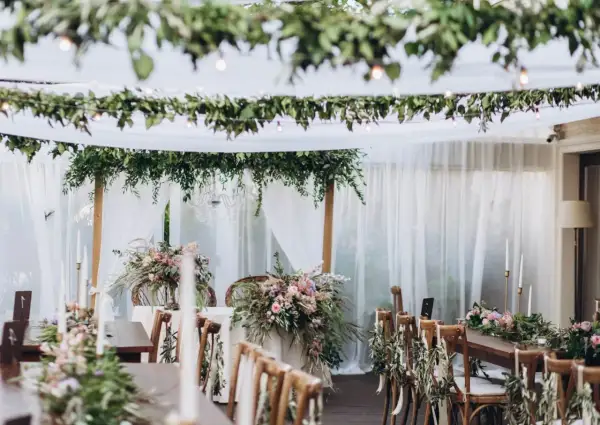 Udekorowane zielenią i kwiatami stoły tworzą magiczny styl boho na wesele. Delikatne tkaniny i girlandy dodają romantyzmu.