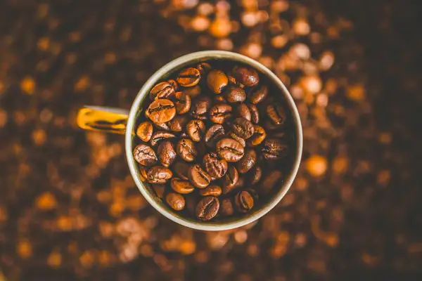 En kopp fylld med rostade kaffebönor, redo att ge dig en rejäl koffeinhaltig kaffeupplevelse.