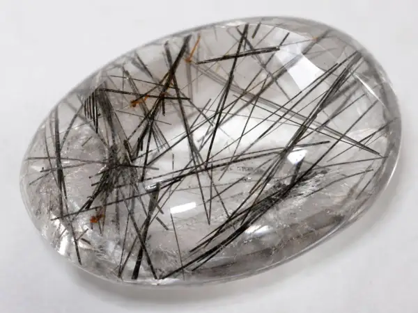 Cuarzo rutilado propiedades: piedra transparente con inclusiones negras y doradas, como un bosque de agujas.