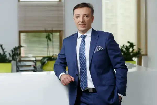 Mężczyzna w granatowym garniturze stoi w nowoczesnym biurze.