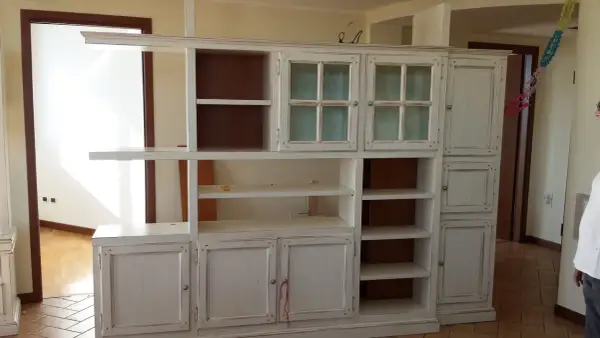 Mobile libreria decapato, con ante a vetro e vani a giorno. Il suo significato è un mobile con finitura effetto invecchiato.