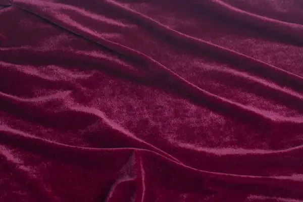 Głęboki, burgundowy rodzaj welwetu, miękko układający się w fałdy, odbijający światło.
