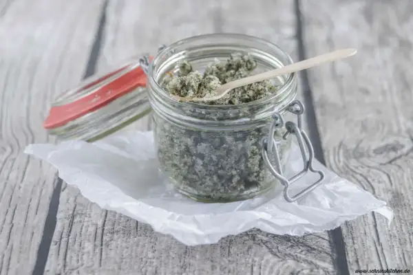 Ein Glas mit selbstgemachtem Kokos Peeling, bereit zur Anwendung. Ein kleiner Holzlöffel liegt darin.
