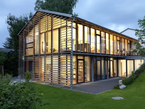 Modernes Haus mit Satteldach, das durch eine Glasfassade und horizontale Lamellen eine neue Interpretation erfährt.