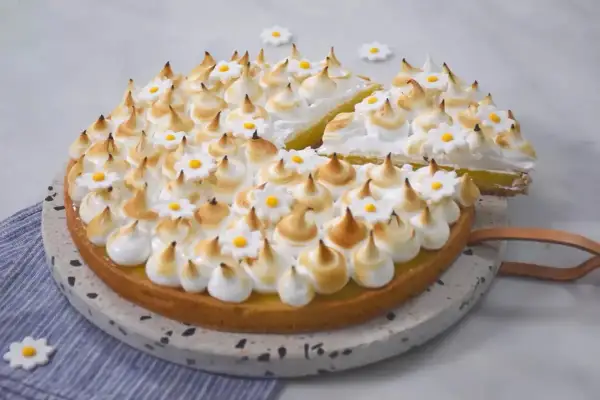 Une délicieuse tarte citron meringuée, ornée de petites fleurs en sucre, prête à être dégustée.