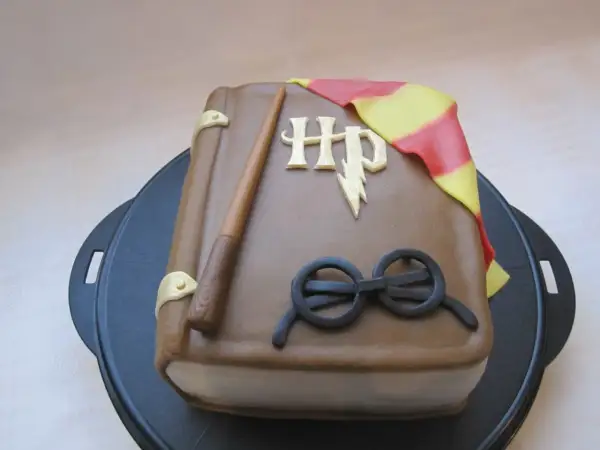 En tårta formad som en bok med Harry Potters trollstav, glasögon och Gryffindors halsduk. Ett magiskt harry potter tårta recept!