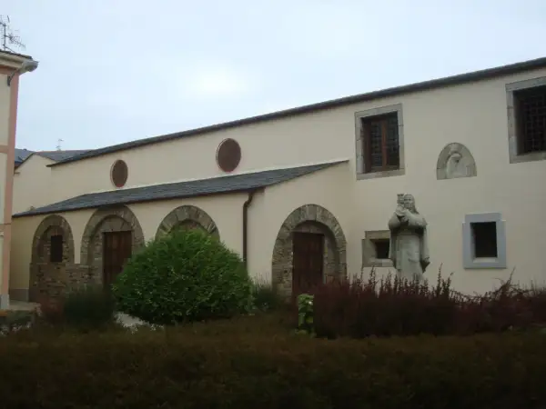 Fachada del convento de Santa Clara en Ribadeo, con arcos de piedra, ventanas y una estatua de monja.