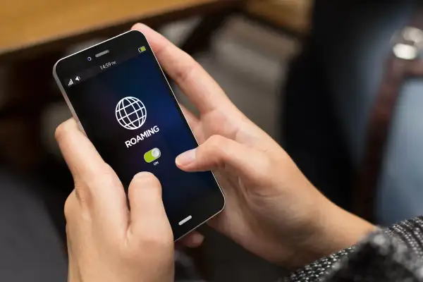 Dłoń włącza roaming na telefonie, przygotowując się do podróży po Czechach.