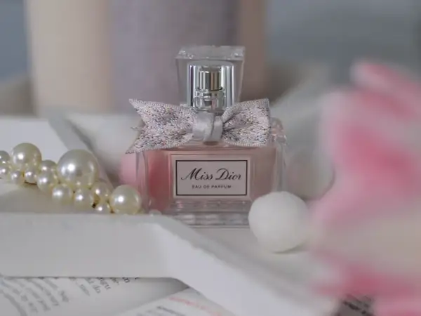Elegancka butelka Miss Dior 100ml z kokardką, otoczona perłami i delikatnymi, białymi kulkami.