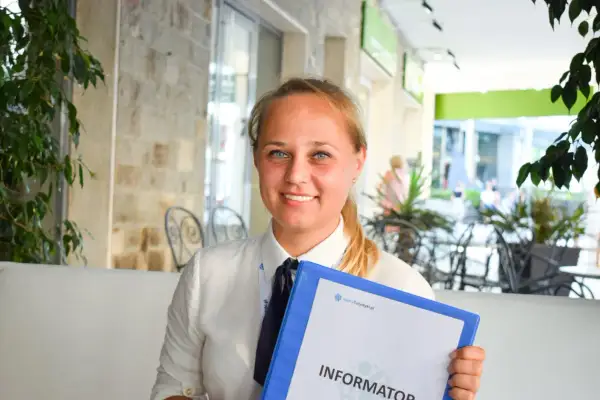 Uśmiechnięta rezydentka z niebieskimi oczami trzyma segregator z napisem "Informator".