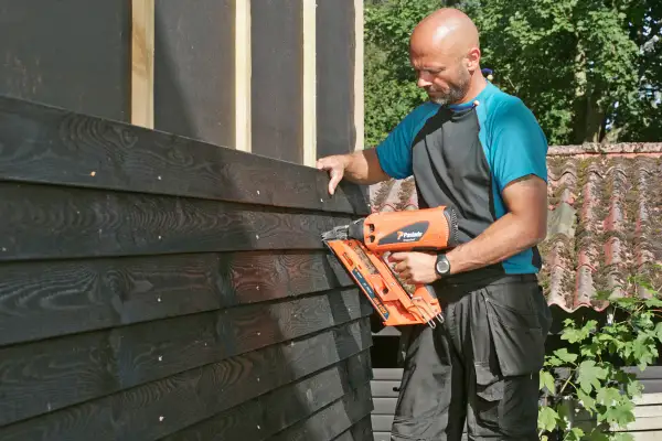 Man monterar liggande panel med spikpistol.