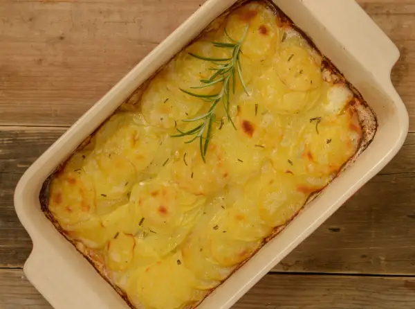 En gyllene pommes anna i en ugnsform, toppad med en rosmarinkvist. Perfekt till helgmiddagen.