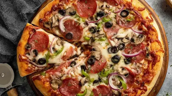 Pyszna pizza z pepperoni, oliwkami, pieczarkami i cebulą, idealna na szybki obiad. Ciasto na proszku do pieczenia sprawia, że jest puszyste i chrupiące.