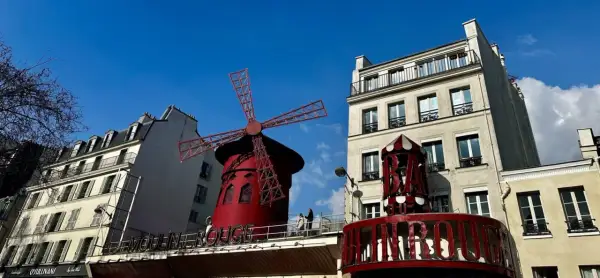 Słynny czerwony wiatrak Moulin Rouge na tle błękitnego nieba.