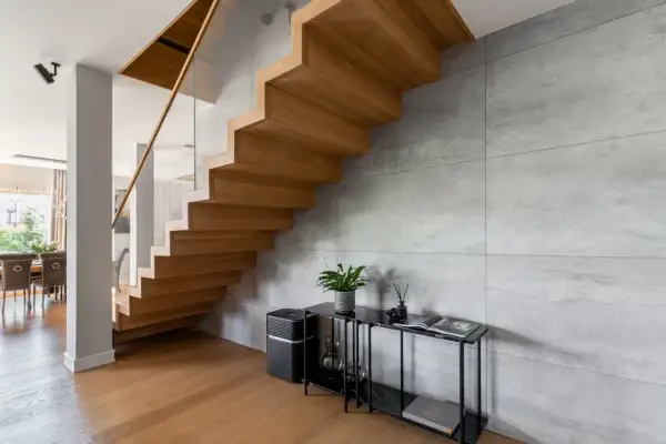 Nowoczesne schody dywanowe z drewna dębowego, szklana balustrada i beton architektoniczny tworzą elegancką przestrzeń.