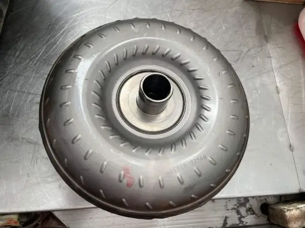 Metalowy element, jeden z rodzajów sprzęgieł, z widocznym numerem seryjnym.