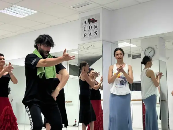 Clase de sevillanas rápidas con un instructor masculino y varias mujeres practicando.