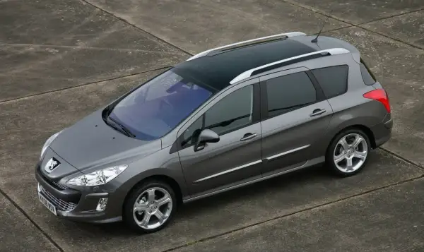 Szary Peugeot 308 SW z 2011 roku z panoramicznym dachem, zaparkowany na betonowej nawierzchni.