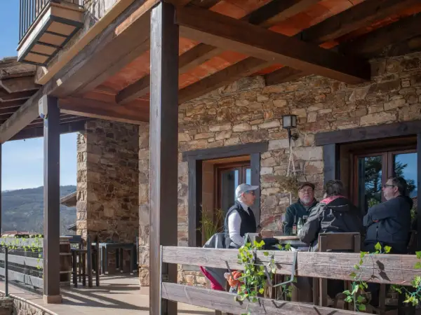 Gente disfrutando en la terraza de uno de los restaurantes de Horcajuelo de la Sierra, con vistas a la montaña.