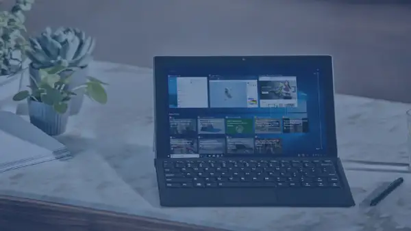 Nowoczesny laptop z klawiaturą i ekranem dotykowym, obok rośliny i stosu papierów. Idealny do pracy, gdy środek trwały od jakiej kwoty jest potrzebny.