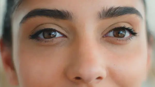 Zbliżenie na oczy kobiety z makijażem typu foxy eyes. Wyraziste brwi i subtelna kreska podkreślają spojrzenie.