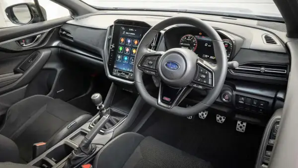 Wnętrze Subaru STI z dużym ekranem dotykowym, cyfrowymi zegarami i sportową kierownicą. Gotowy na jazdę!