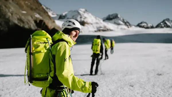Bergsteiger mit leuchtend gelber Ausrüstung und Rucksäcken auf einer Gletscherwanderung. Die Packliste für die Hochtour ist komplett.