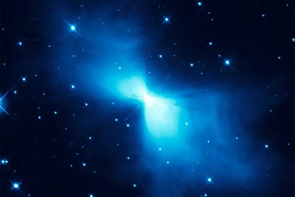 En lysande blå nebulosa, likt en fjäril, lyser upp den mörka rymden. Stjärnor glittrar runt den, en påminnelse om den extrema temperatur rymden kan ha.