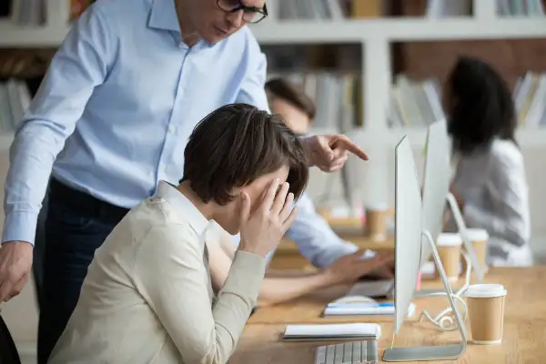 Uomo punta il dito contro collega in lacrime, un esempio di come provare il mobbing in ufficio.