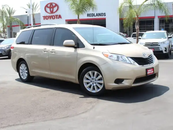 Złoty minivan Toyota Sienna 2025 na tle salonu Toyota.
