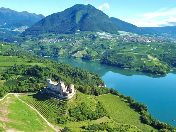Castello di Thun domina il lago e i vigneti del Val di Non. Un paesaggio incantevole da esplorare, tra storia e natura.