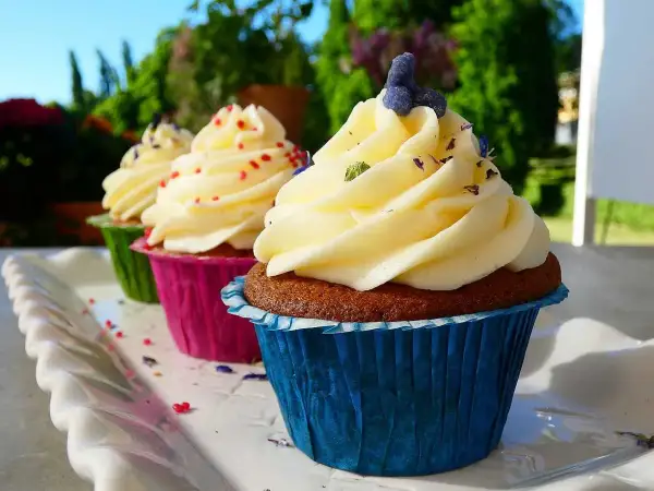 Tre cupcakes med fluffig frosting, dekorerade med strössel och lavendel. Perfekt frosting till cupcakes för en solig dag.